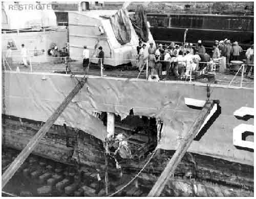 Taken in dry dock Sasebo, Japan. Japanese yard workers assembled for briefing on bow removal. Severe mine damage below water line from mine explosion.